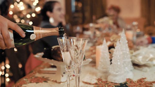 Person Pouring Champagne in the Glasses at Dinner Table
