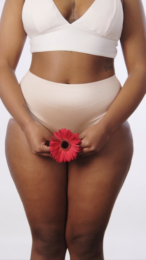 A Woman in White Bikini Holding a Red Daisy