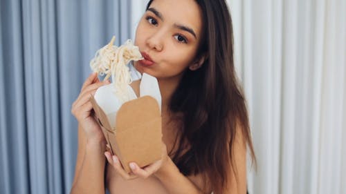 Young Woman Eating Noodles With Chopsticks