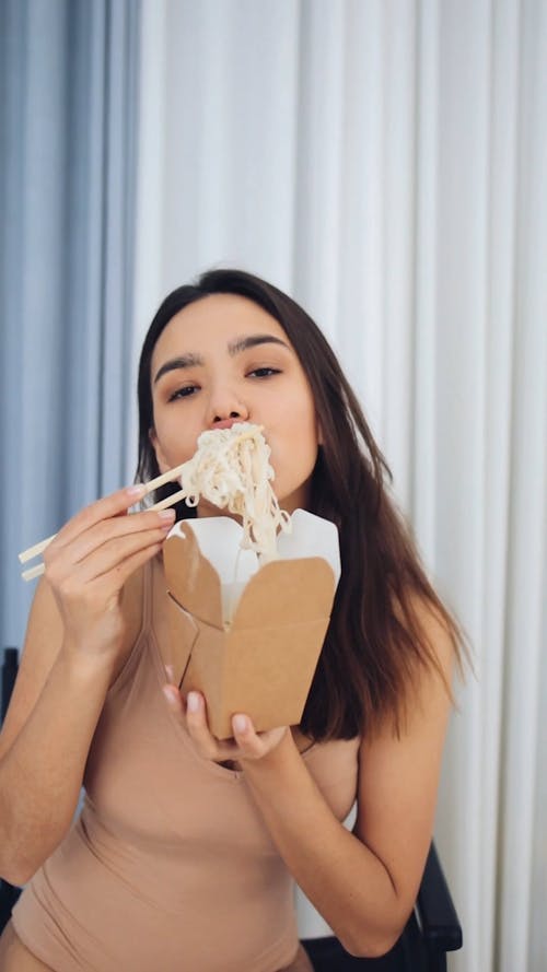 Young Woman Eating Noodles With Chopsticks