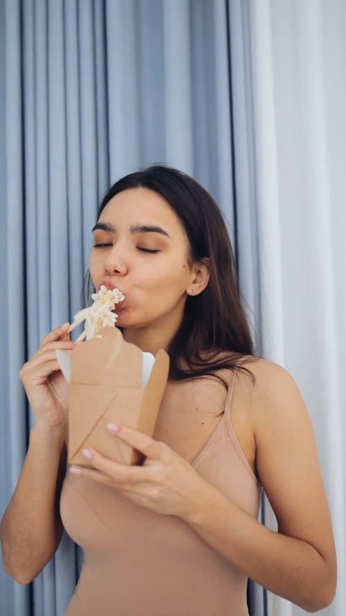 Young Woman Eating Noodles With Chopsticks