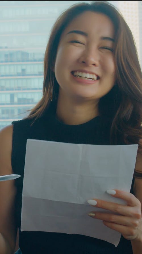 A Happy Woman Holding a Pen and Paper