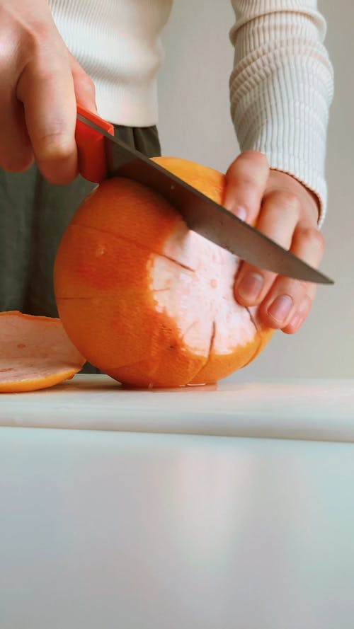 A Person Slicing the Orange Using a Knife