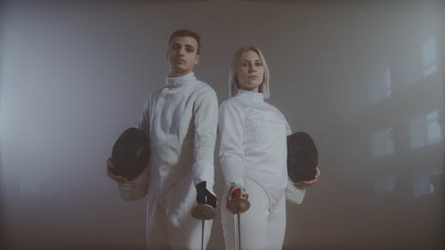 A Man and Woman Posing with Fencing Gears
