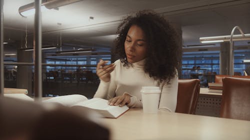 Woman Studying while Drinking a Cup of Coffee