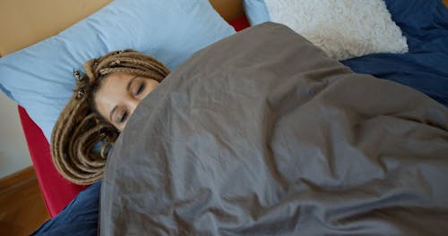 A Woman Lying Down the Bed While looking at the Camera