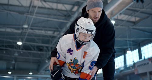 Man Teaching Boy How to Play Ice Hockey