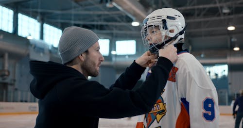 Man Helping Boy with Helmet