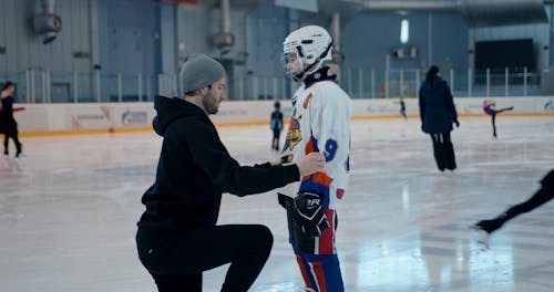 Man Helping Boy with Hockey Gear