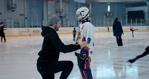 Man Helping Boy with Hockey Gear