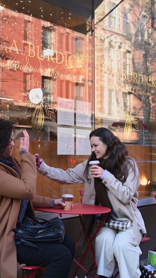 Woman Taking Selfie while Having Coffee with Friend