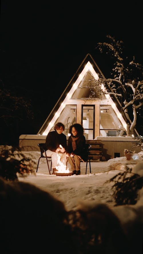 A Couple Sitting Outside the House at Night