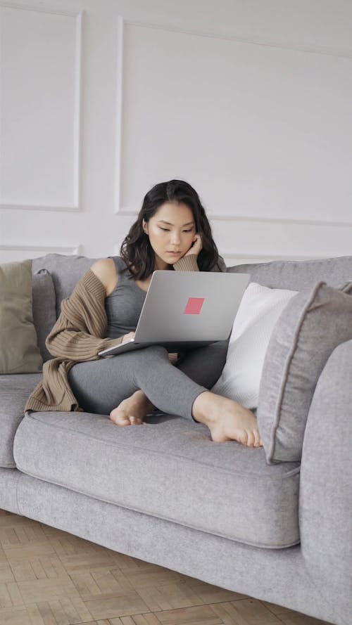 Woman on Couch Looking at Computer Laptop
