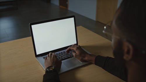 Man Typing on Laptop with Blank Screen