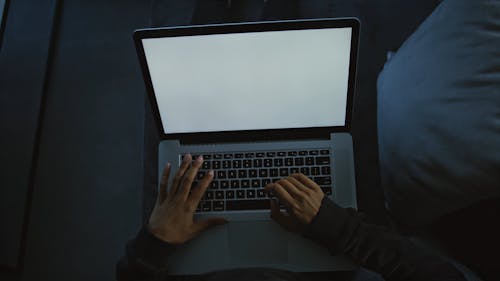 Woman Typing on Laptop with Blank Screen