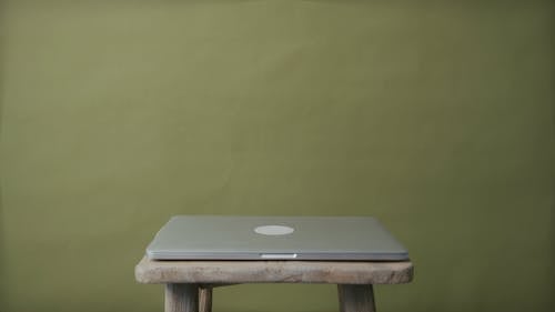 A Woman Opening a Laptop on Top of a Wooden Chair