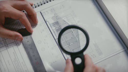 A Person Looking at the Floor Plan Using a Magnifying Glass