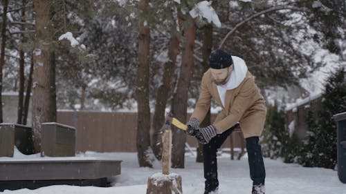 Man Splitting Firewood in the Snow