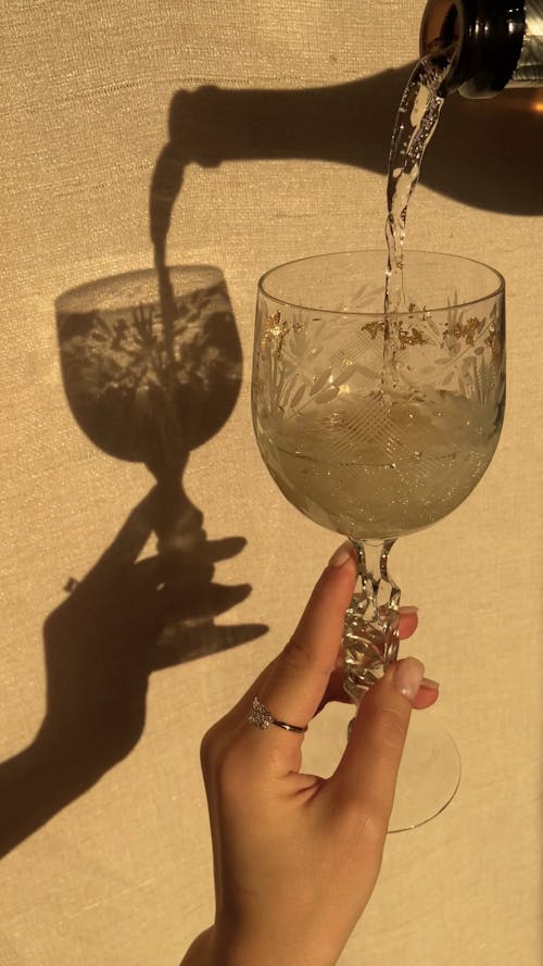 Person Pouring Beverage In a Crystal Glass