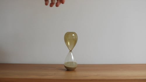 A Video of a Person Flipping a Hourglass on Top of a Wooden Table