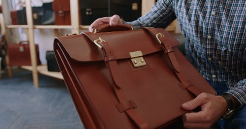 A Man Handing Over a Leather Bag to a Woman