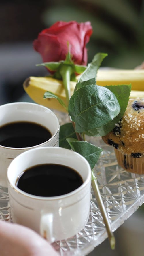 Person Carrying a Tray of Coffee and Cupcake with Red Rose