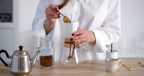 A Person Pouring Coffee Powder into a Coffee Dripper