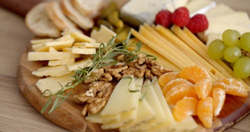 Variety of Cheese Slices and Fruits on Wooden Tray