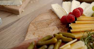 person putting a slice of blue cheese on wooden tray