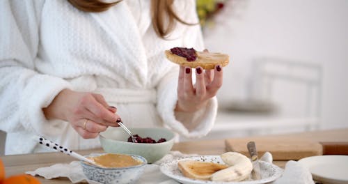 A Person Putting Jam on a Bread 