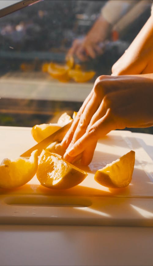Person Slicing Oranges on a Chopping Board