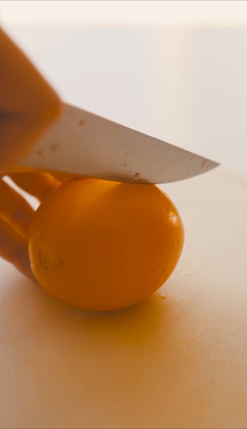 Person Slicing an Orange in Half