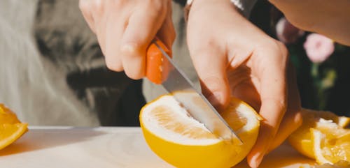 Person Slicing an Orange with Knife