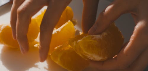 A Person Putting the Tangerines on a Glass Bowl
