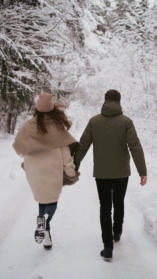A Couple Holding Hands in the Snow Field
