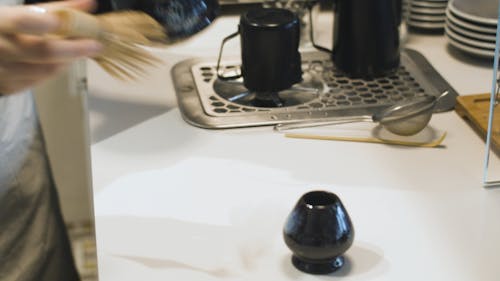 A Person Mixing a Matcha using a Bamboo whisk