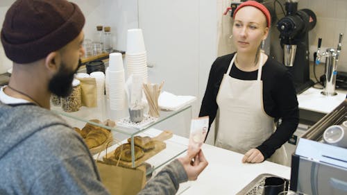 A Woman Taking a Customer's Payment at a Cashier