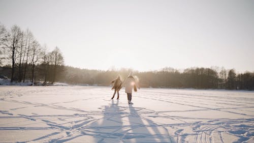 A Couple Skating in Frozen Lake in the Middle of the Forest