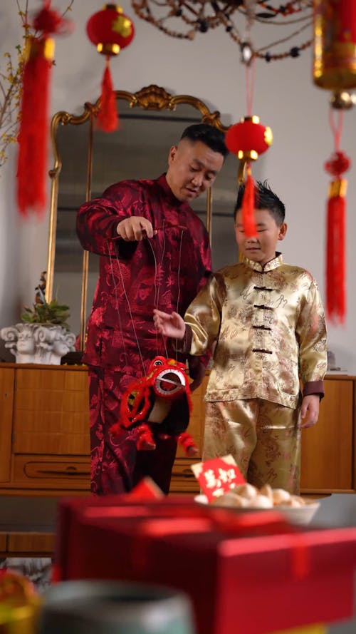 A Father And Son Playing With A Lion Dance Puppet