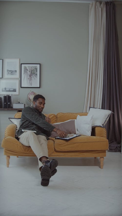 A Man Sitting in a Couch while Counting Money