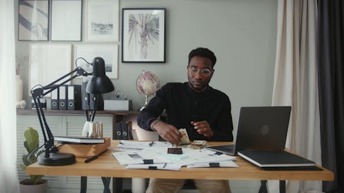 Man Counting Money on Work Desk