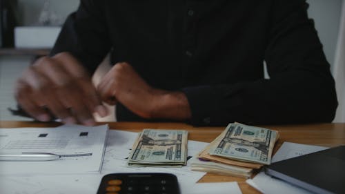 A Man Counting Bank Notes Using Calculator