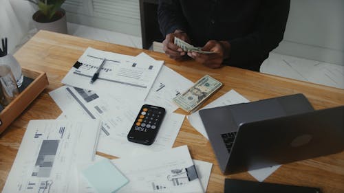 Man Counting Money on Work Desk