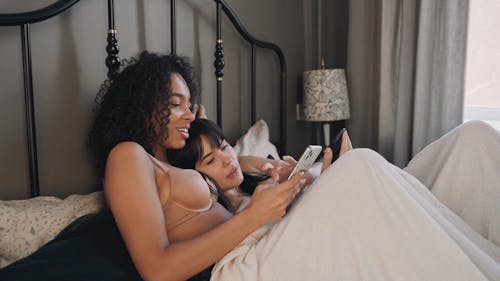 Young Couple Using Smartphones in Bed