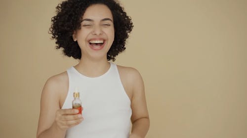 A Happy Woman Holding A Bottle Of Essential Oil