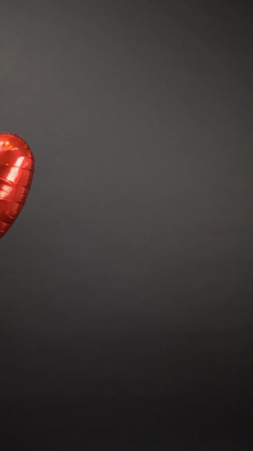 Two Persons Holding Two Red Heart Shaped Balloons