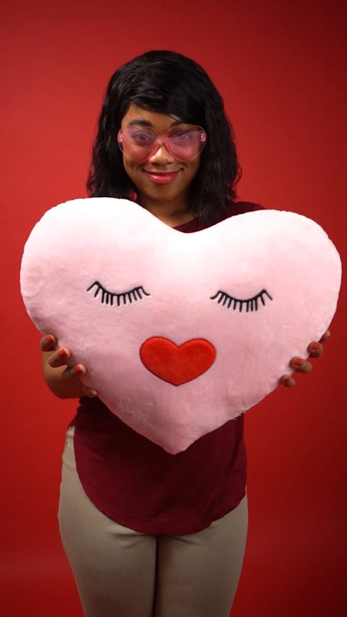 Woman Holding a Pink Heart Shaped Pillow