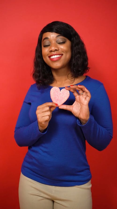 Woman in Blue Long Sleeve Shirt Holding a Heart Shaped Cookie