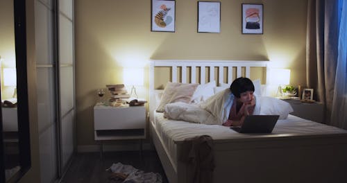 Woman Watching from her Laptop in her Bedroom