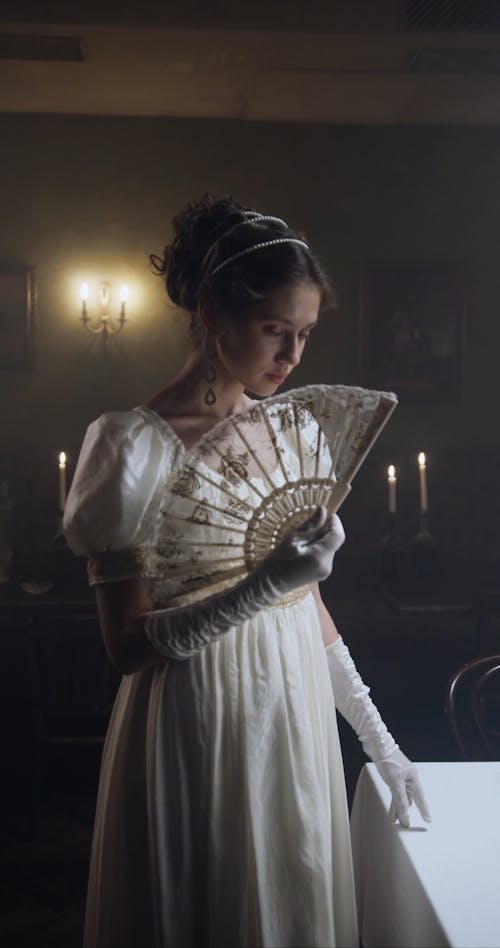 A Woman Standing and Fanning a Brise Fan While Looking at Camera